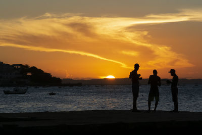 Silhouette of young people jumping from the crush bridge at the yellow sunset.