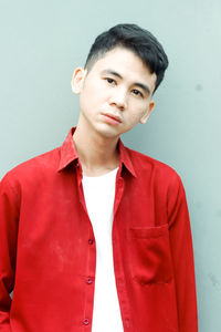 Portrait of young woman standing against yellow wall