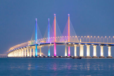 Illuminated colorful penang bridge over strait of malacca against clear sky at dusk