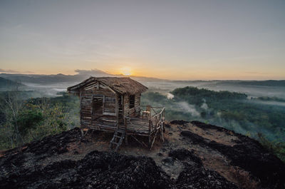 Abandoned house on landscape against sky during sunset