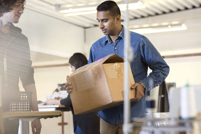 Man carrying box while walking by volunteers at workshop