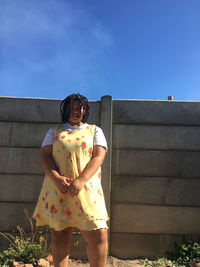 Portrait of woman standing against blue sky