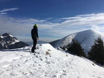 Man standing on snowcapped mountain against sky