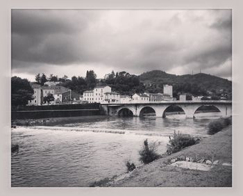 Bridge over river against cloudy sky