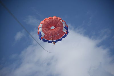 Low angle view of woman paragliding against sky