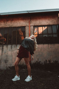 Rear view of woman standing by building in city