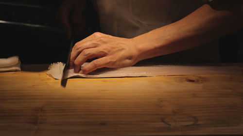 Midsection of man cutting fish at table