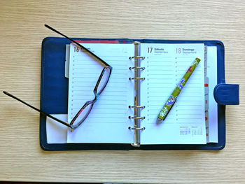 Directly above shot of objects of eyeglasses with diary on table