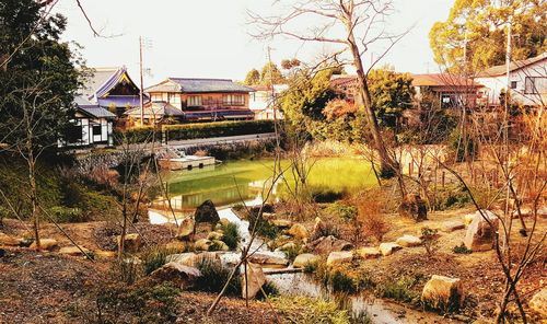 Houses by trees and buildings against sky