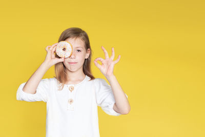 Young woman holding toy against yellow background