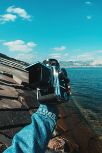 Man photographing by sea against sky