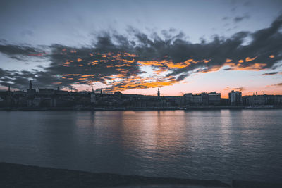 Scenic view of sea by buildings against sky at sunset