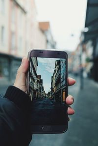 Midsection of man using mobile phone in city