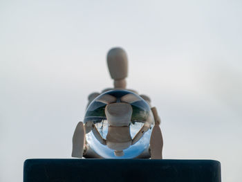 Close-up of crystal ball and figurine against sky