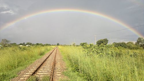 Scenic view of rainbow over field against sky