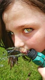 Close-up portrait of cute girl drinking water from hose