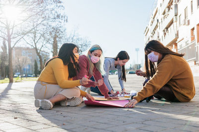 Females wearing mask writing on banner on street