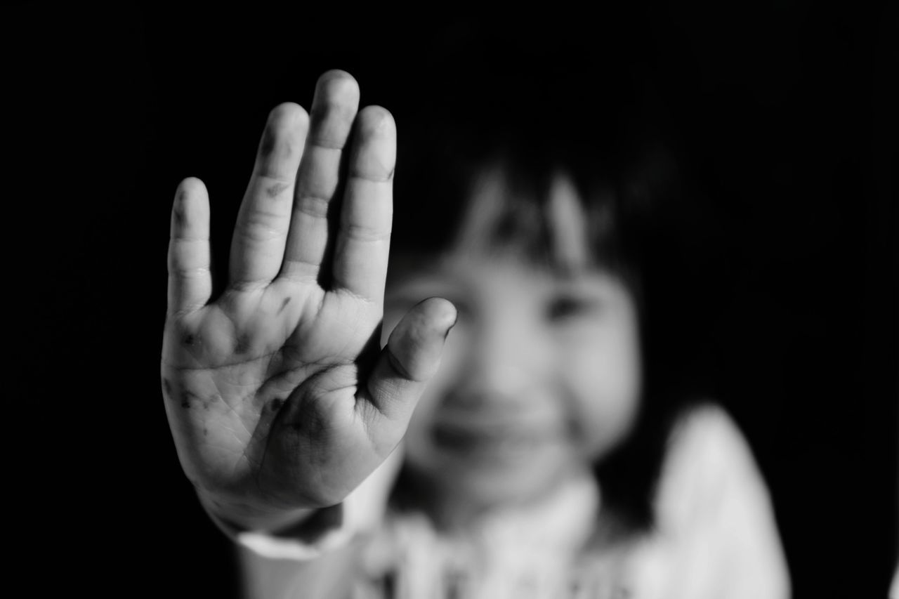 one person, headshot, child, black background, childhood, gesturing, hand, portrait, front view, human body part, studio shot, human hand, indoors, focus on foreground, real people, innocence, stop gesture, body part, finger, aggression