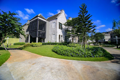 Lawn by building against blue sky