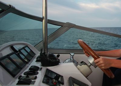 Close-up of hand on boat sailing in sea against sky