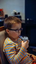 Portrait of boy holding inhalator at home