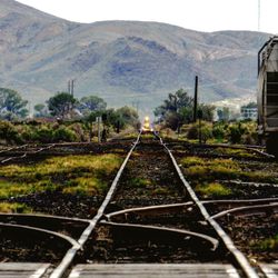 Railroad track by mountain against sky