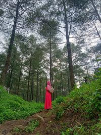 Photo of woman wearing hijab and red dress in the forest