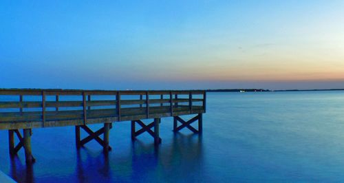 Pier in sea at sunset