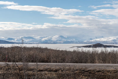 Scenic view of field by lake against sky