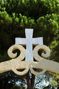 Close-up of cross sign against trees
