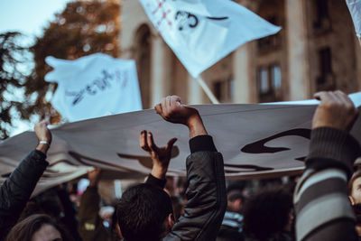 Rear view of people with arms raised in city