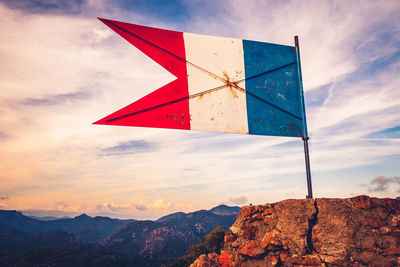 French flag on mountain against sky during sunset