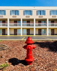 Red fire hydrant on field against building in city