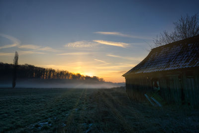 House on field against sky during sunset