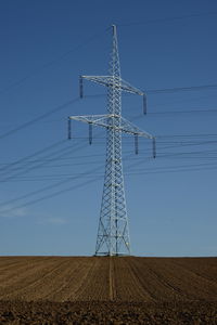 Low angle view of electricity pylon against clear sky