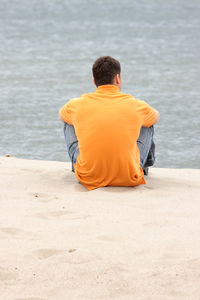 Rear view of man sitting on beach