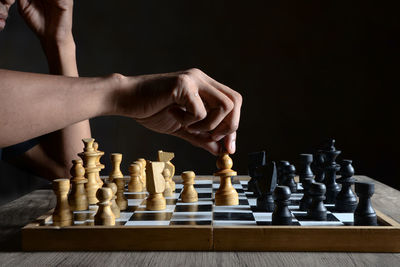 Low angle view of man playing chess against black background