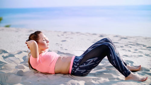 Low section of woman exercising at beach