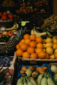 Fruit stand detail with fresh oranges, bananas, a pineapple and more fresh fruit in daylight
