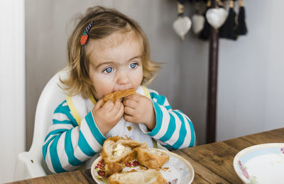 Cute girl eating bread at home