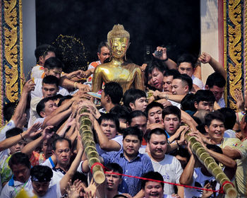 People by buddha statue in city during event