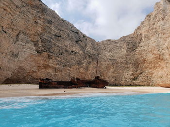 Shipwreck on beach by rock formation