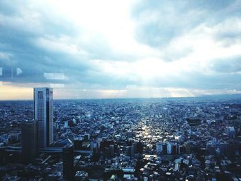 Aerial view of cityscape against cloudy sky