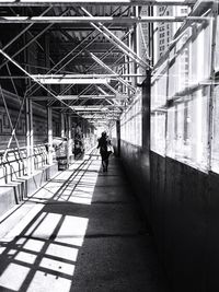 Rear view of man walking on footbridge in city