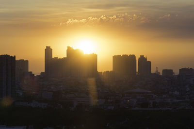 Buildings in city against sky during sunset