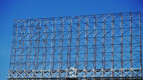 Low angle view of chainlink fence against blue sky