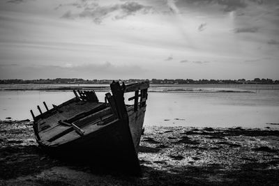 Abandoned boat on beach against sky