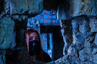 Portrait of young woman using mobile phone against wall