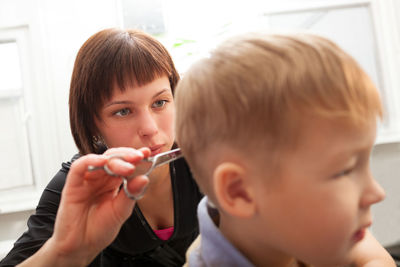 Cute boy having haircut at barber shop