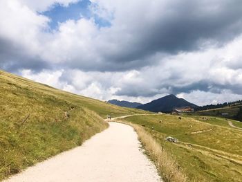 Road amidst field against sky